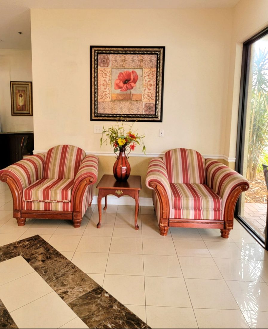 Sitting area near the front entrance with two striped chairs and framed artwork at Sunny Hills in Homestead